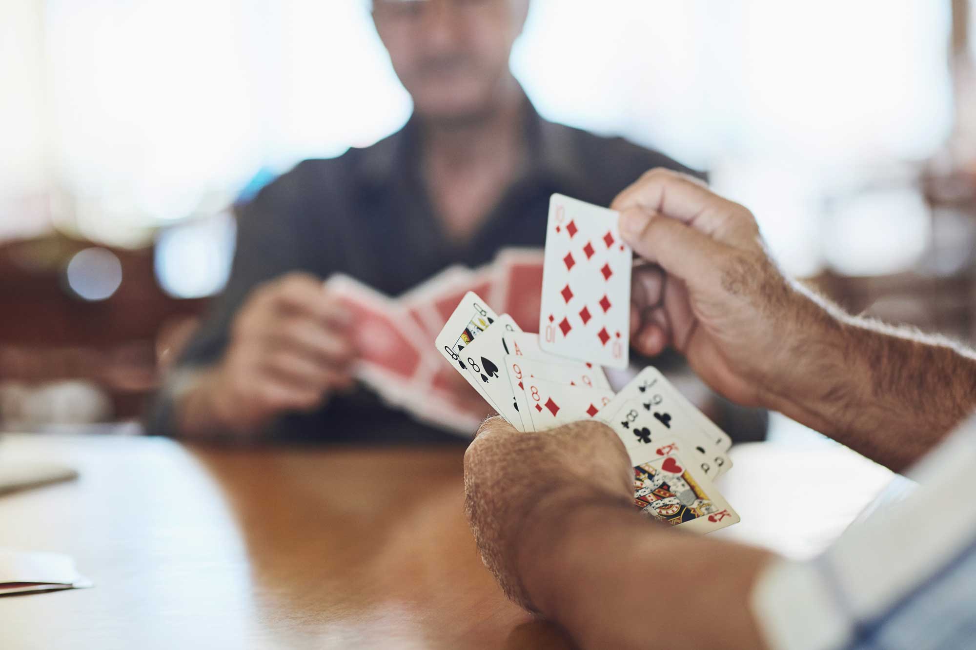 Personer spelar kort vid ett träbord