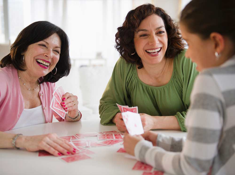 En grupp personer sitter vid ett bord och spelar kort.