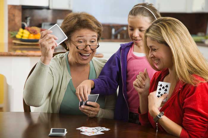 En gammal dam och två barn spelar kort