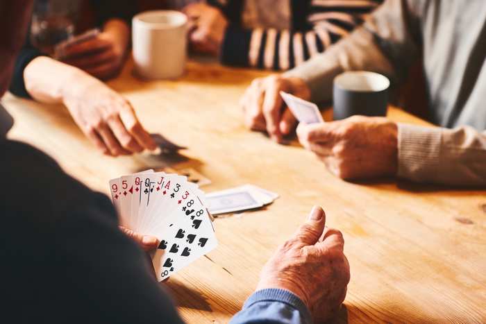 En grupp personer spelar kort vid ett bord.