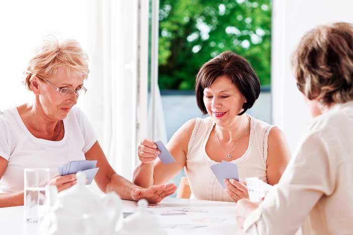 Tre äldre kvinnor spelar kort